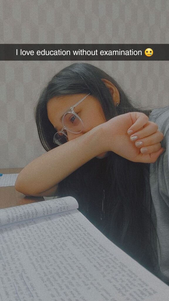 Girl resting her head on her arm while studying, wearing glasses, with the caption "I love education without examination 🫠" above her.
